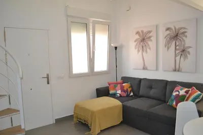a living room with a gray couch and a window at Apartamento en Playa Victoria in Cádiz
