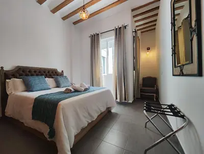 a bedroom with a bed with blue pillows and a chair at Suite del Mercado Little Apartments in Cádiz