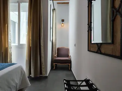 a bedroom with a mirror and a chair next to a bed at Suite del Mercado Little Apartments in Cádiz