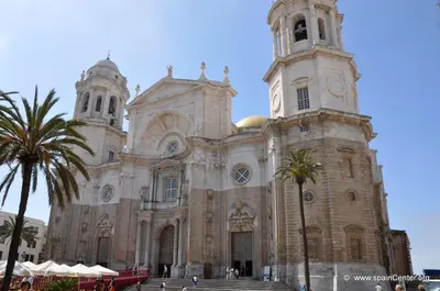 a church with two towers and a palm tree in front at Suite del Mercado Little Apartments in Cádiz