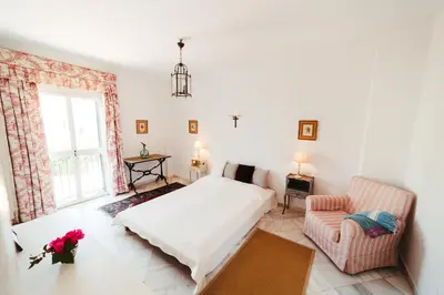a white bedroom with a bed and a chair at Andalusian beach haven villa in El Puerto de Santa María