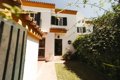 a white house with black windows and a fence at Andalusian beach haven villa in El Puerto de Santa María