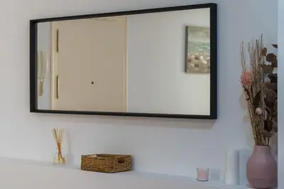 a mirror on a wall above a shelf with flowers at Casa Palacio la Mar Salá in El Puerto de Santa María