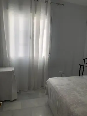 a white bedroom with a bed and a window at Centro de Sanlúcar in Sanlúcar de Barrameda