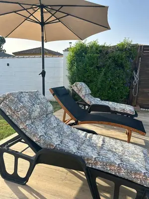 two lounge chairs and an umbrella on a patio at Casa Manolete in Chiclana de la Frontera