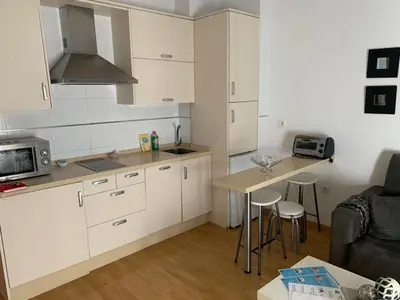 a kitchen with white cabinets and a table with stools at ARCO PLAZA DE ESPAÑA CADIZ in Cádiz