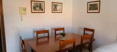 a dining room with a wooden table and chairs at Apartamento céntrico JARDINES DE LA INFANTA, con garaje privado in Sanlúcar de Barrameda