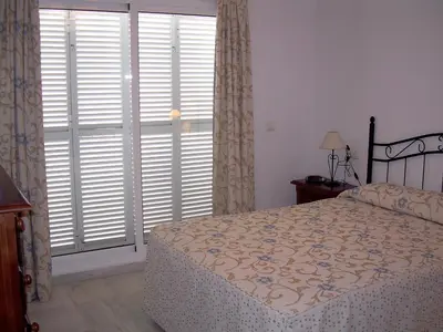 a bedroom with a bed and a large window with shutters at Apartamento céntrico JARDINES DE LA INFANTA, con garaje privado in Sanlúcar de Barrameda