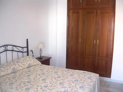 a bedroom with a bed and a wooden cabinet at Apartamento céntrico JARDINES DE LA INFANTA, con garaje privado in Sanlúcar de Barrameda
