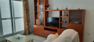 a living room with a tv and a entertainment center at Apartamento céntrico JARDINES DE LA INFANTA, con garaje privado in Sanlúcar de Barrameda