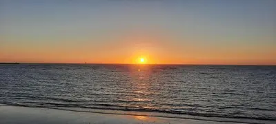 a sunset on the beach with the sun setting at Apartamento céntrico JARDINES DE LA INFANTA, con garaje privado in Sanlúcar de Barrameda