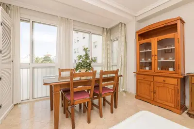 a dining room with a table and chairs and windows at Playamar in Cádiz