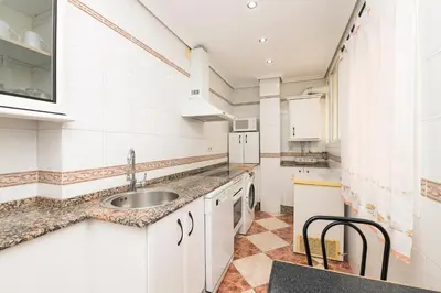 a kitchen with white cabinets and a sink at Playamar in Cádiz