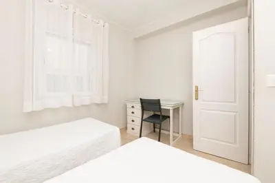 a bedroom with two beds and a desk with a chair at Playamar in Cádiz