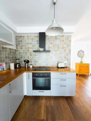 a kitchen with white cabinets and a wooden floor at Magnífico Dúplex Nueva Andalucía, 3 habitaciones y vistas a la playa in Sanlúcar de Barrameda