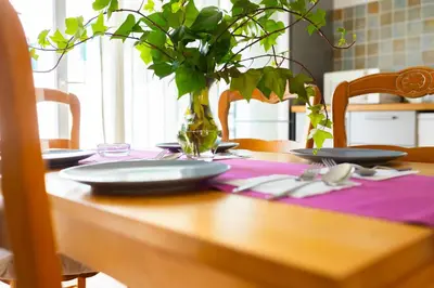 a table with plates and a vase with a plant at Magnífico Dúplex Nueva Andalucía, 3 habitaciones y vistas a la playa in Sanlúcar de Barrameda