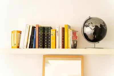 a shelf with books and a globe on it at Magnífico Dúplex Nueva Andalucía, 3 habitaciones y vistas a la playa in Sanlúcar de Barrameda