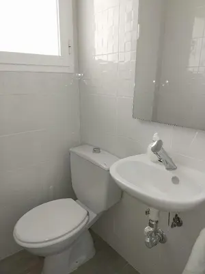 a white bathroom with a toilet and a sink at Brisas de Puerto Real in Puerto Real