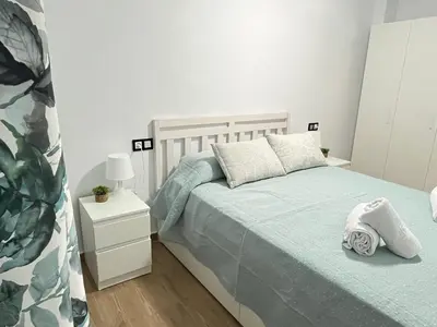 a white bedroom with a bed and a night stand at Adana Beach House in Cádiz