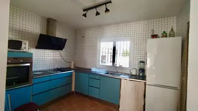 a kitchen with blue cabinets and a white refrigerator at villa rana verde in Chiclana de la Frontera