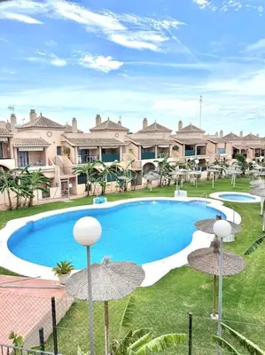 a swimming pool with umbrellas in front of a house at Unifamiliar Chiclana, La Barrosa in Chiclana de la Frontera