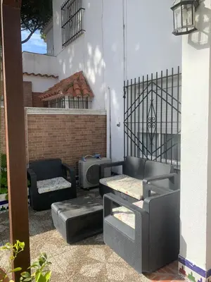 a patio with a couch and a chair at Casa en la playa 750 m La Barrosa in Cádiz