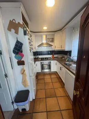 a kitchen with white cabinets and a tile floor at Casa en la playa 750 m La Barrosa in Cádiz