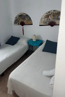 two beds in a room with a blue table at Casa en la playa 750 m La Barrosa in Cádiz