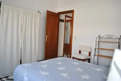 a bedroom with a bed and a window and a chair at Apartamento LUNA in Arcos de la Frontera