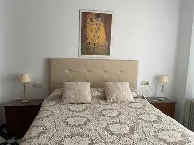 a bedroom with a bed with two lamps and a painting at Apartamento LUNA in Arcos de la Frontera