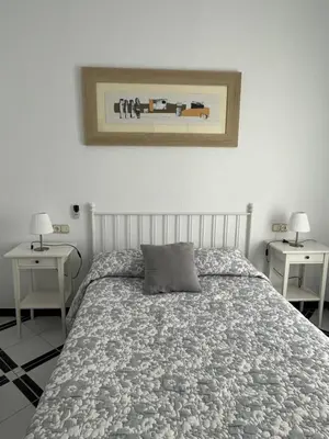 a bedroom with a bed and two tables with lamps at Apartamento LUNA in Arcos de la Frontera