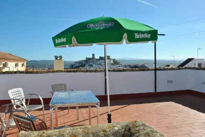 a green umbrella on a patio with chairs and a table at Apartamento SOL in Arcos de la Frontera