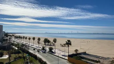 a view of a beach with palm trees and a road at La ilusión de Pepa in El Puerto de Santa María