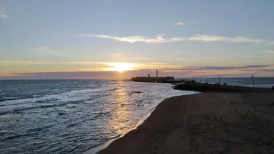 a sunset over a beach with the sun setting at Piso en la Caleta in Cádiz