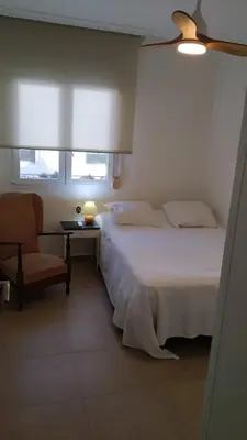 a bedroom with a bed and a chair and a window at Piso en la Caleta in Cádiz