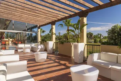 a patio with white couches and chairs on a deck at Elba Costa Ballena Beach & Thalasso Resort in Costa Ballena