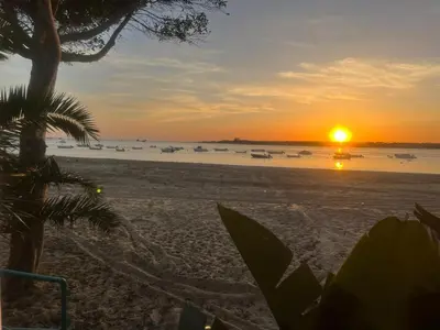 a sunset on the beach with boats in the water at Mi Paraiso in Sanlúcar de Barrameda