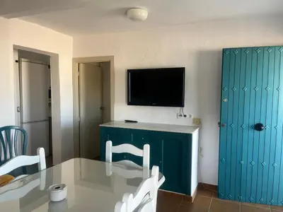 a room with a table and a flat screen tv at Mi Paraiso in Sanlúcar de Barrameda