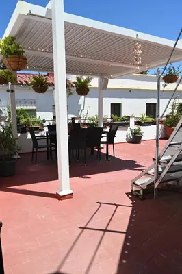 a patio with a table and chairs under a pergola at Bienvenidos a San Miguel in Jerez de la Frontera