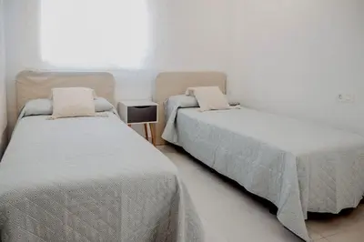 two beds in a white room with a window at AZURE - Ático dúplex in Chipiona