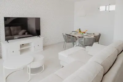 a white living room with a couch and a table at AZURE - Ático dúplex in Chipiona