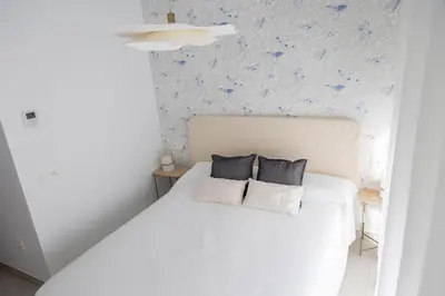 a bedroom with a white bed with two pillows at AZURE - Ático dúplex in Chipiona