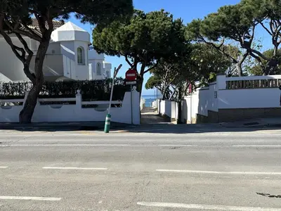 an empty street with a white house and trees at Casita en La Barrosa, Complejo Atlántico in Chiclana de la Frontera