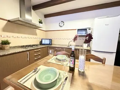 a kitchen with a table with plates and wine glasses at Casita en La Barrosa, Complejo Atlántico in Chiclana de la Frontera