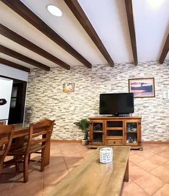 a living room with a flat screen tv on a brick wall at Casita en La Barrosa, Complejo Atlántico in Chiclana de la Frontera