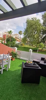 a patio with chairs and a table and grass at Kalma Vivienda vacacional la barrosa Chiclana Cadiz in Chiclana de la Frontera