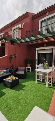 a backyard with green grass and a red house at Kalma Vivienda vacacional la barrosa Chiclana Cadiz in Chiclana de la Frontera