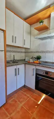 a kitchen with white cabinets and a sink and a stove at Kalma Vivienda vacacional la barrosa Chiclana Cadiz in Chiclana de la Frontera