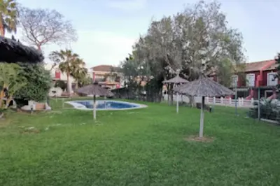 a yard with umbrellas and a swimming pool at Kalma Vivienda vacacional la barrosa Chiclana Cadiz in Chiclana de la Frontera