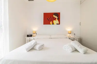 a white bedroom with a white bed with two pillows at Allo Apartments San Clemente Parking Piscina Centro 2 Habitaciones in Jerez de la Frontera